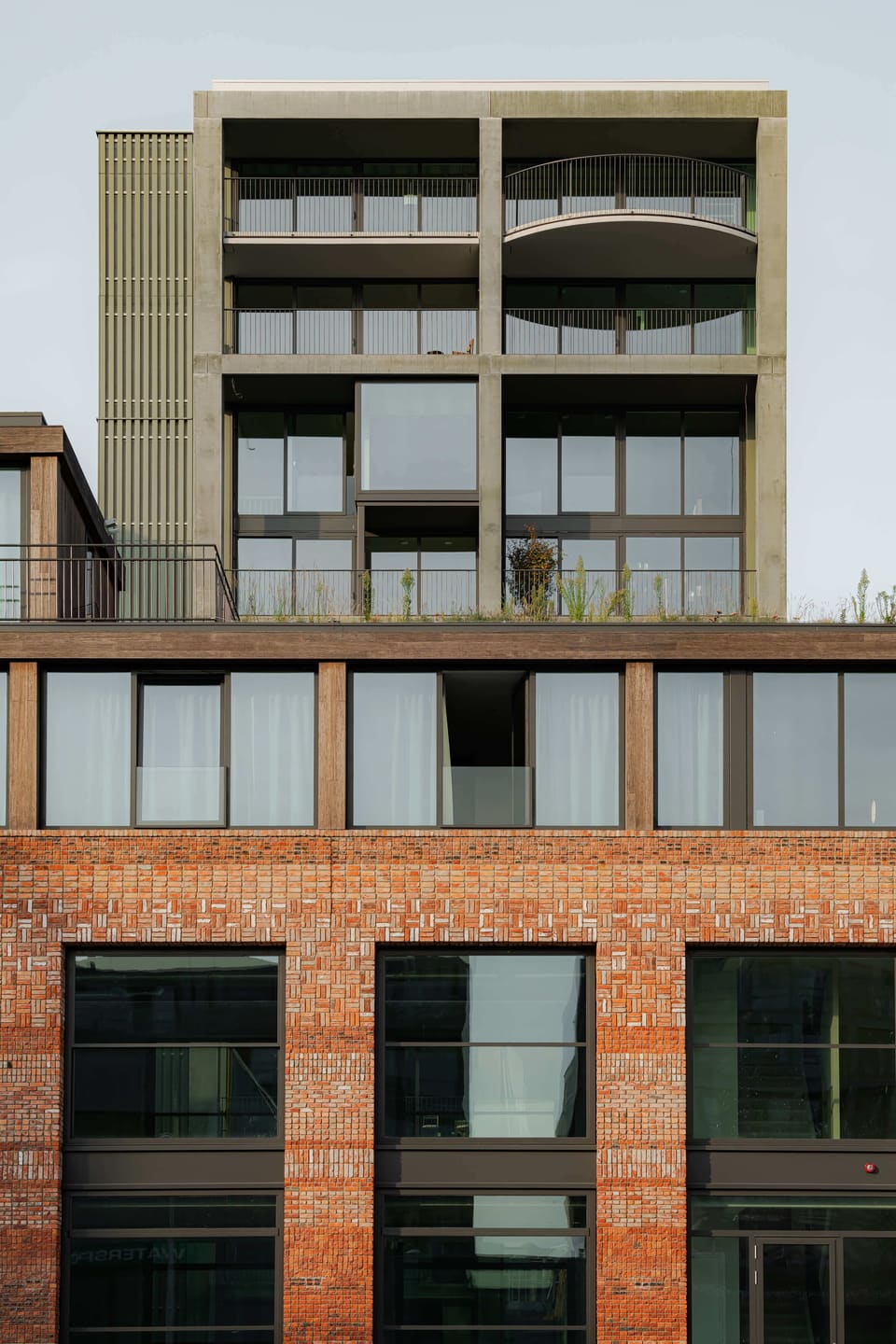 The recycled-brick building with the top of the green Superlofts tower behind it