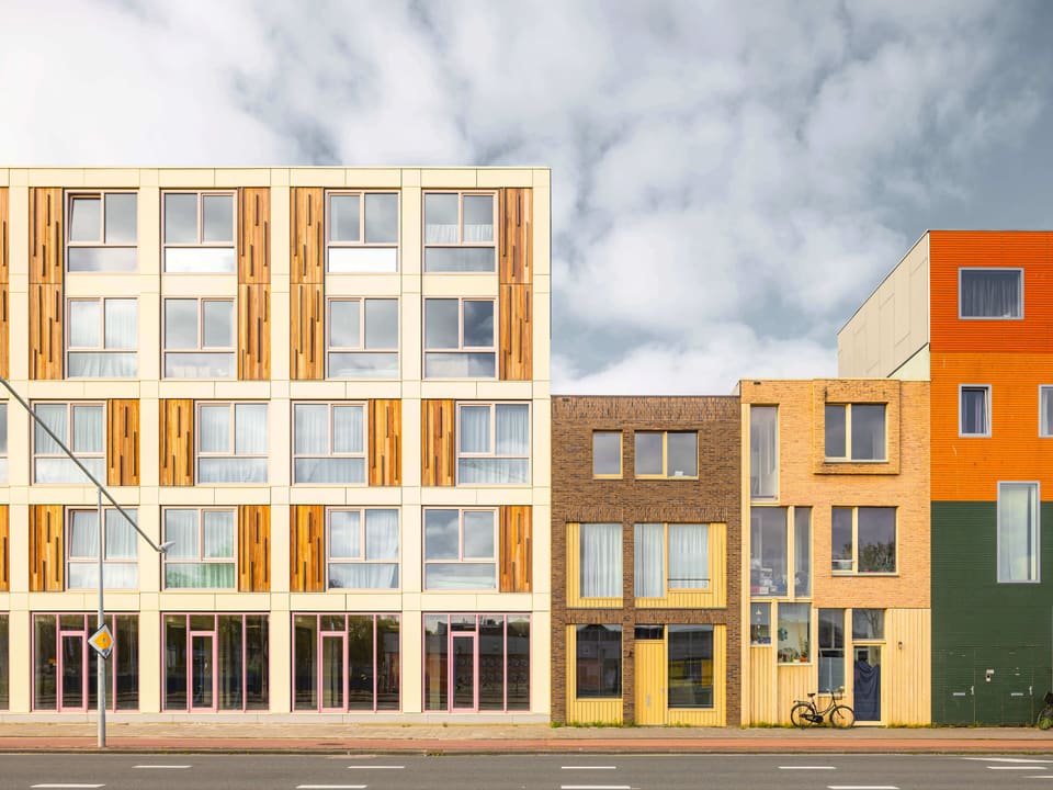 Poppies: timber-clad modular apartment building with colourful facade panels along a street in Amsterdam-Noord